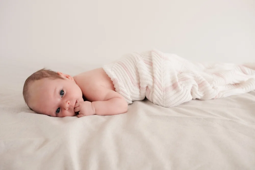 Baby auf einer hellen Decke beim Newbornshooting.